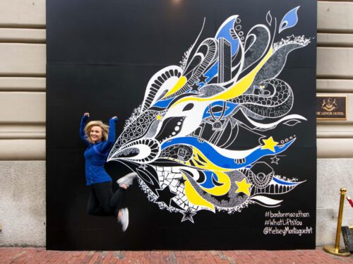 Catering Sales Manager, Taylor Marshall, poses in front of the finished Marathon Mural
