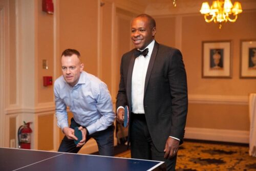 Groom and guest play ping pong at wedding reception