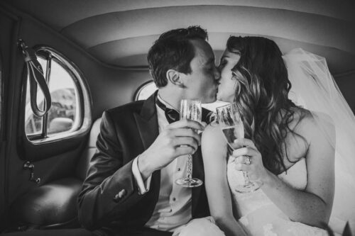 Bride and groom toast in a car