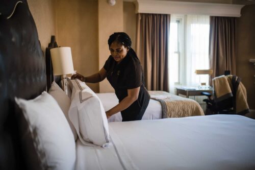 Housekeeper making the bed in guest room